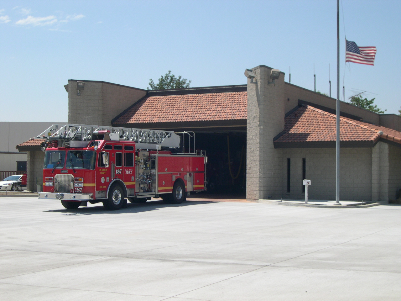 Firetruck 187 parked outside its station. American flag raised high next to it.