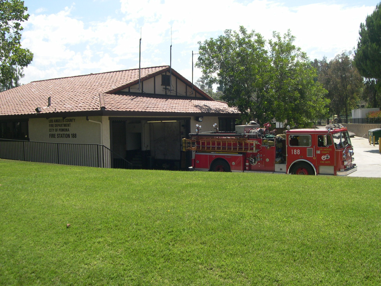 Firetruck 188 parked outside of its' station. Beautiful grass and trees surrounds the truck.